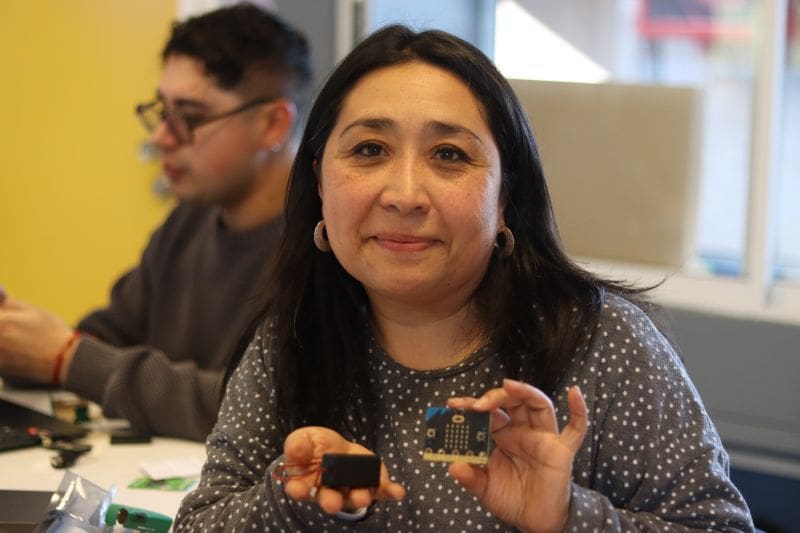 Foto de una Docente primera vez experimentando con un BBC micro:Bit en capacitación.